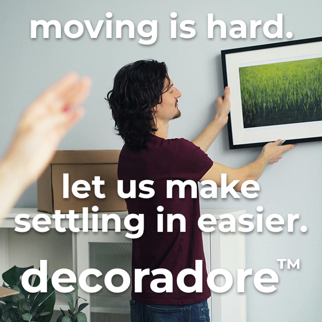 An image showing someone hanging up a painting, with text overload that reads moving is hard. let us make settling in easier. decoradore.